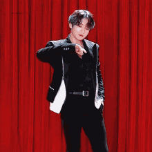 a man in a black suit is standing in front of a red curtain with the words ' infinite love ' on the bottom