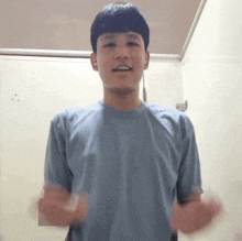 a young man in a blue shirt is standing in front of a wall