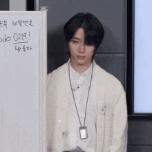 a young man stands in front of a white board with the number 0219 on it