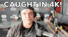 a man wearing headphones stands in front of a microphone with the words caught in 4k behind him