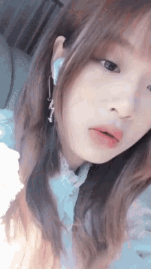 a close up of a woman 's face with a white shirt and earrings