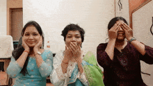 three women are covering their faces with their hands