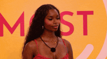 a woman in a red dress stands in front of a large pink most sign