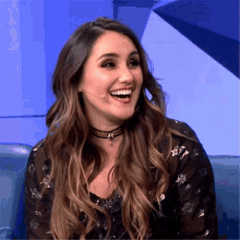 a woman with long hair and a choker smiles