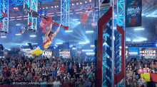 a man is doing a trick in front of a crowd at a ninja warrior competition