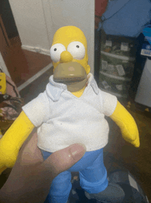 a person is holding a homer simpson doll with a white shirt and blue pants