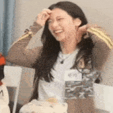a woman is laughing while sitting at a table with a name tag on her neck .
