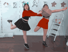 two girls are dancing in front of a wall with balloons that say r and a