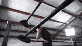 a man is hanging upside down on a bar in a ring