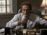 a man in a white shirt and tie is drinking from a can