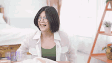 a woman wearing glasses is sitting at a table and smiling