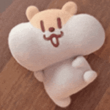 a stuffed animal is laying on a wooden floor with a big mouth .