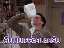 a man is drinking milk from a container with a foreign language written on the bottom