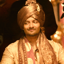 a man wearing a turban and a scarf looks at the camera