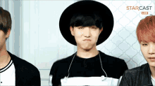 a man wearing a black hat is making a funny face in front of a sign that says starcast live