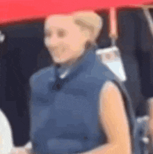 a blurry picture of a woman wearing a blue vest and holding an umbrella .