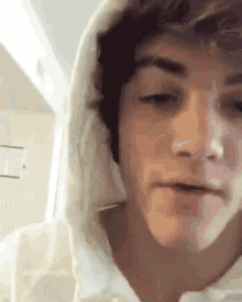 a close up of a young man wearing a hoodie and looking at the camera .
