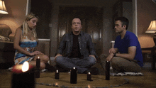 a man and two women are sitting in a circle with candles around them