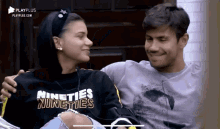 a man and a woman are sitting next to each other and the woman is wearing a nineties nineties sweatshirt