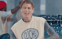 a man wearing a shirt with the word cliche on it is smiling
