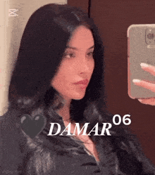 a woman is taking a selfie in front of a mirror with the name damar on the bottom right