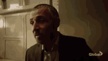 a man in a suit is sitting in front of a refrigerator and talking to someone .