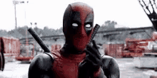 a man in a deadpool costume is holding a gun in his hand .