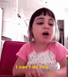 a little girl is sitting at a table and says i can 't do this .