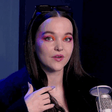 a woman with sunglasses on her head is standing in front of a microphone and pointing at her hair