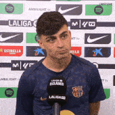 a man in a laliga shirt stands in front of a laliga tv microphone