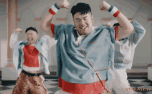 a man in a blue shirt is dancing in front of a sign that says " whea aya ya "