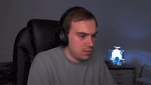 a man wearing headphones is sitting in a chair in front of a desk .