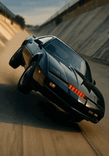 a black car with red lights on the front is driving down a dirt road