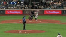 a baseball game is being played in front of a large fred meyer sign