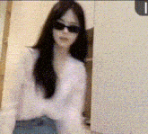 a woman wearing sunglasses and a white shirt is standing in a room