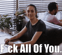 a woman sits at a table with the words " f * ck all of you " written below her