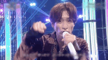 a young man is singing into a microphone on a stage