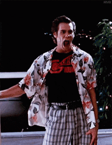 a man in a hawaiian shirt and plaid shorts is screaming with his mouth open .