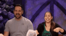 a man and a woman are sitting next to each other on a stage laughing .