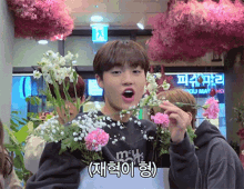 a boy in a black sweatshirt holds a bouquet of flowers in his hand