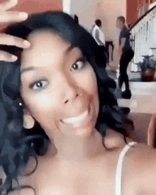 a woman with long black hair is smiling and taking a selfie in a living room .