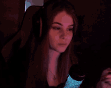 a young woman wearing headphones and a necklace looks at the camera