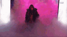 a silhouette of a person standing in front of a pink background surrounded by smoke .