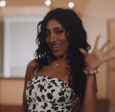 a woman wearing a dalmatian print dress is smiling and waving