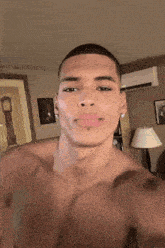 a shirtless man is taking a selfie in a room