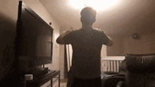 a man is dancing in a living room in front of a television .