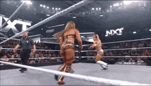 two women wrestling in a ring with nxt written on the wall behind them