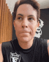 a man wearing a raiders tank top makes a face