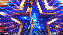 a man and a woman are performing aerial acrobatics in front of a blue star .