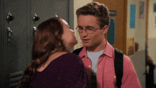 a man and a woman are kissing in front of lockers in a hallway